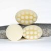 Three pale yellow massage shampoo bars with raised nodules, displayed on a natural gray stone against a white background.